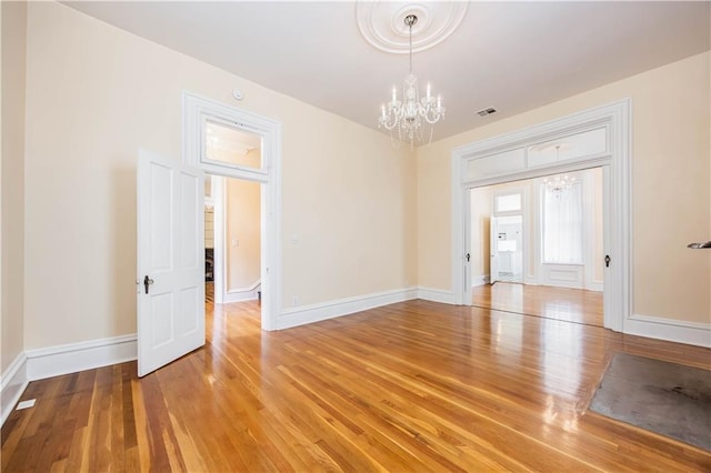 spare room featuring hardwood / wood-style flooring and a notable chandelier