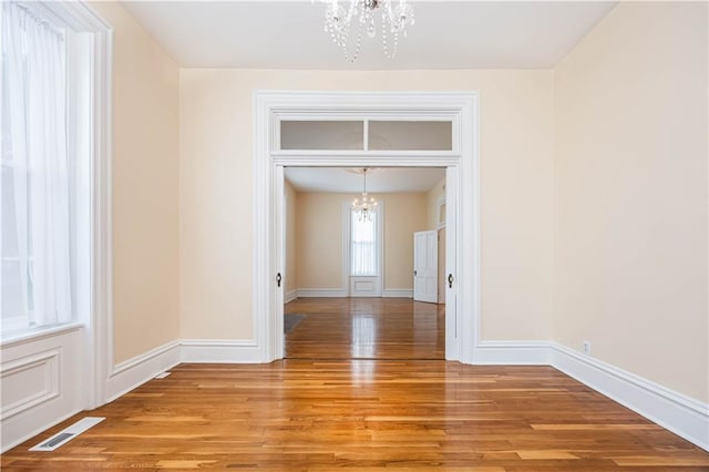 unfurnished dining area featuring a notable chandelier and light hardwood / wood-style flooring