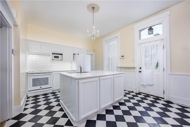 kitchen featuring sink, a wealth of natural light, white cabinets, and white appliances