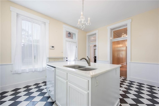 kitchen with sink, white cabinetry, hanging light fixtures, dishwasher, and a kitchen island with sink