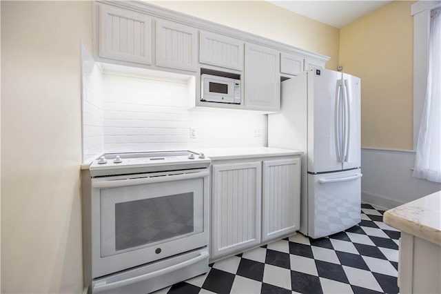 kitchen featuring tasteful backsplash, white appliances, and white cabinets