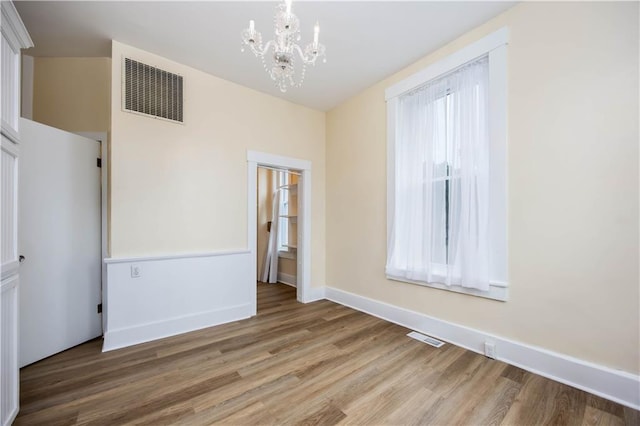 spare room featuring an inviting chandelier and wood-type flooring