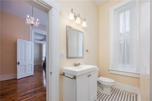 bathroom with vanity, wood-type flooring, an inviting chandelier, and toilet