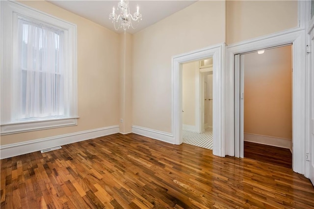 unfurnished room featuring dark wood-type flooring and a chandelier