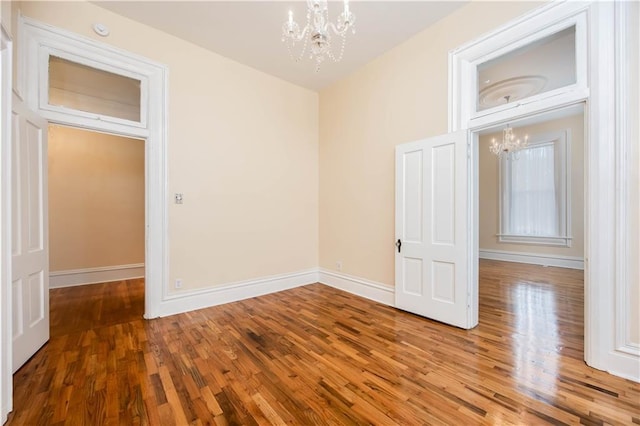 empty room with hardwood / wood-style floors and an inviting chandelier