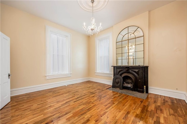 unfurnished living room featuring a chandelier and light wood-type flooring