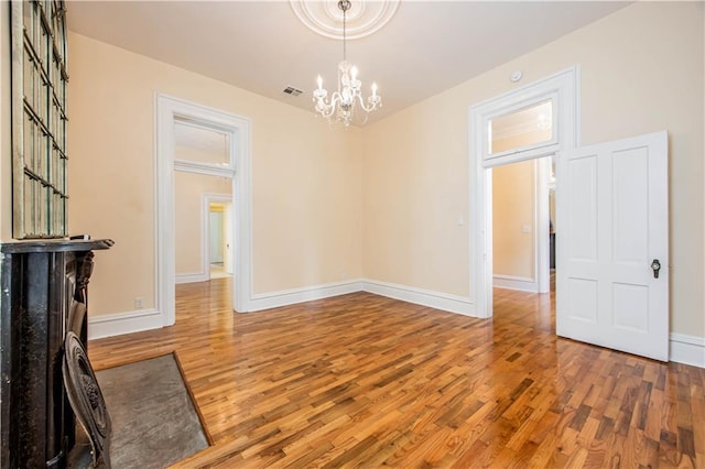 spare room with an inviting chandelier and wood-type flooring