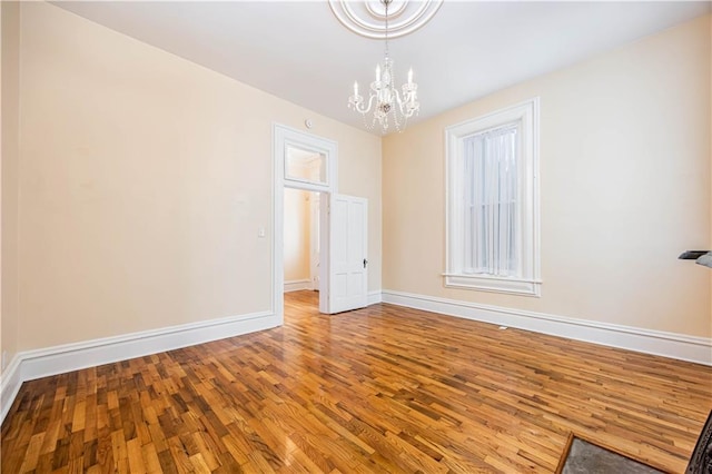 empty room featuring a notable chandelier and wood-type flooring