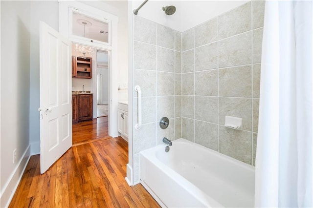 bathroom featuring hardwood / wood-style flooring, tiled shower / bath, and vanity