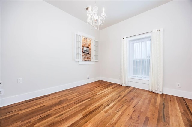 unfurnished room featuring wood-type flooring and a chandelier