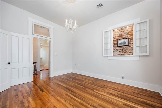 spare room featuring a notable chandelier and wood-type flooring