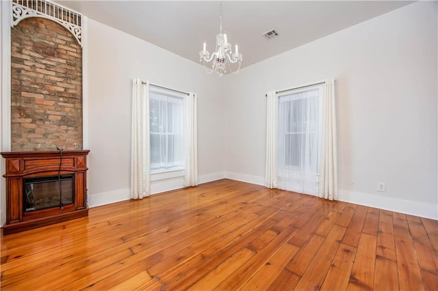 unfurnished living room featuring a chandelier and light wood-type flooring