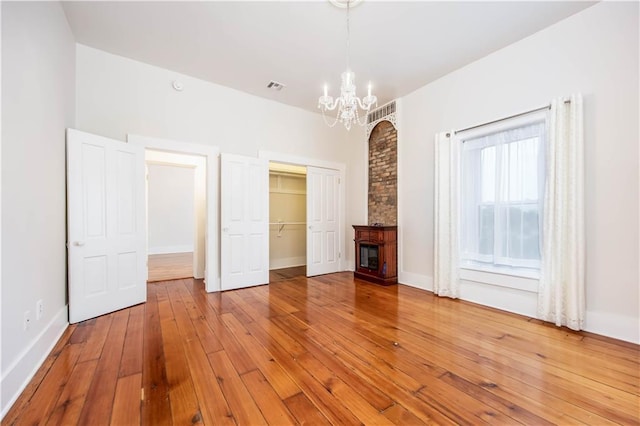 unfurnished bedroom with a chandelier, hardwood / wood-style floors, and a closet