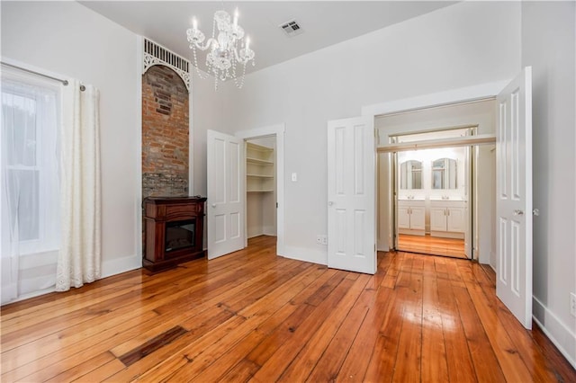 unfurnished living room featuring a fireplace, a chandelier, and light wood-type flooring