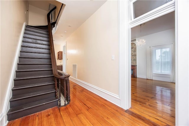 stairs with a notable chandelier and hardwood / wood-style flooring