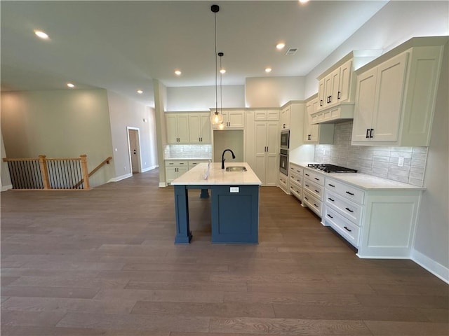 kitchen with hanging light fixtures, sink, tasteful backsplash, a center island with sink, and dark hardwood / wood-style floors