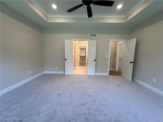 unfurnished bedroom with ornamental molding, ceiling fan, a raised ceiling, and light carpet