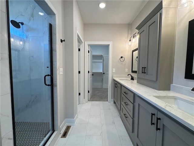 bathroom featuring marble finish floor, double vanity, a spacious closet, a sink, and a shower stall