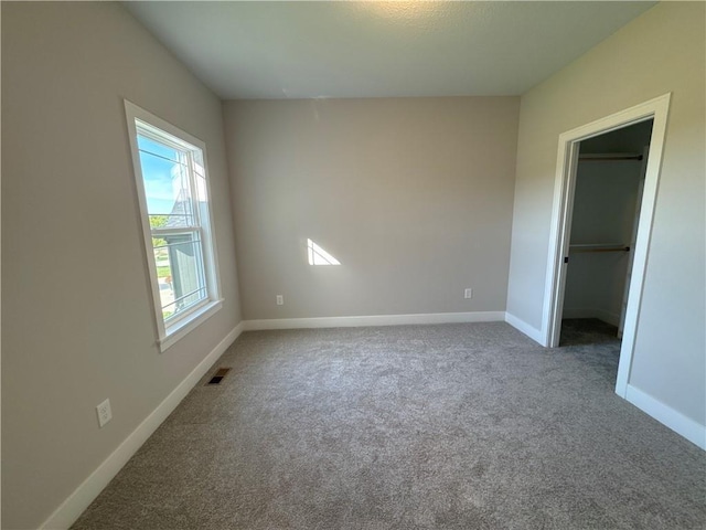 interior space featuring carpet floors, baseboards, a spacious closet, and visible vents