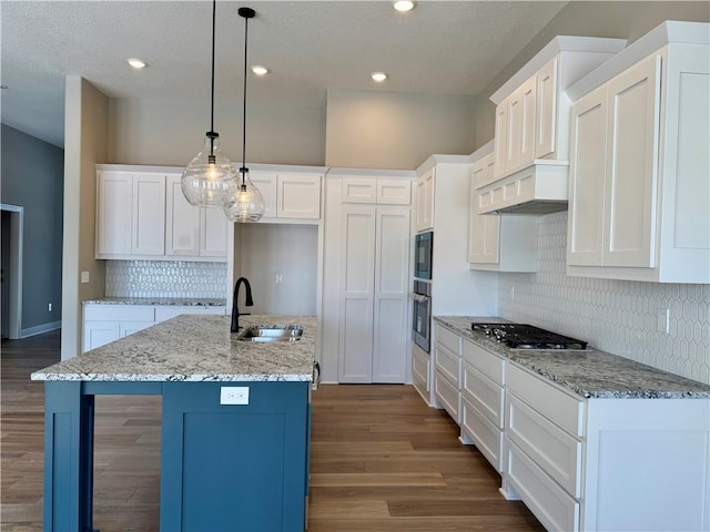 kitchen with stainless steel gas cooktop, dark wood-style flooring, a sink, hanging light fixtures, and white cabinets