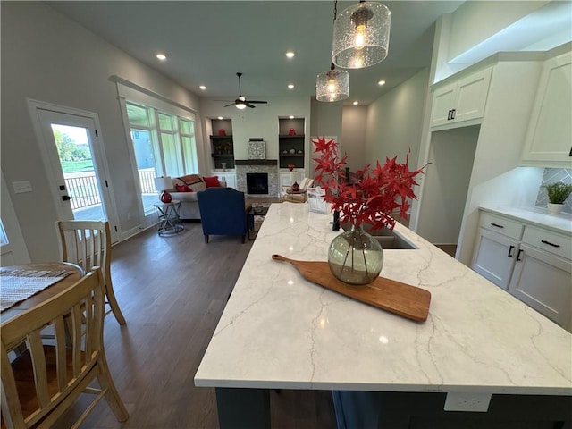 dining area featuring a fireplace, dark wood-type flooring, and ceiling fan