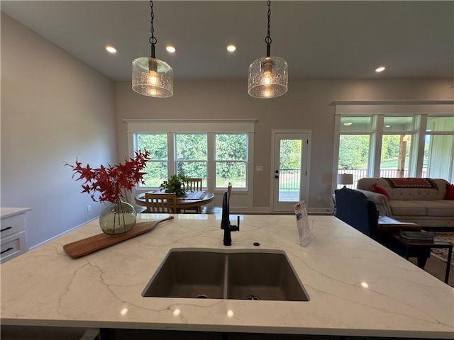 kitchen with a kitchen island with sink, sink, and decorative light fixtures