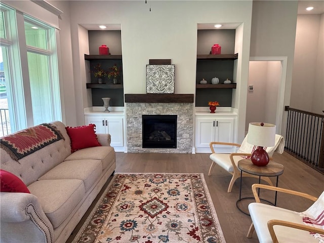 living room featuring built in shelves, hardwood / wood-style flooring, and a fireplace