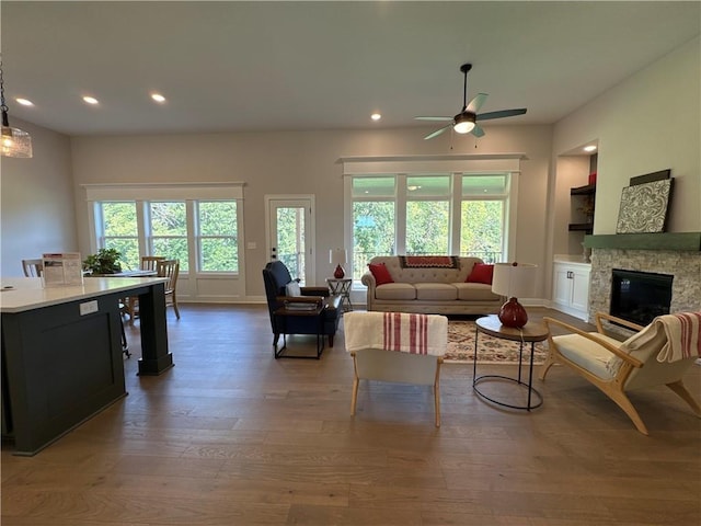 living room featuring hardwood / wood-style floors, ceiling fan, and a fireplace