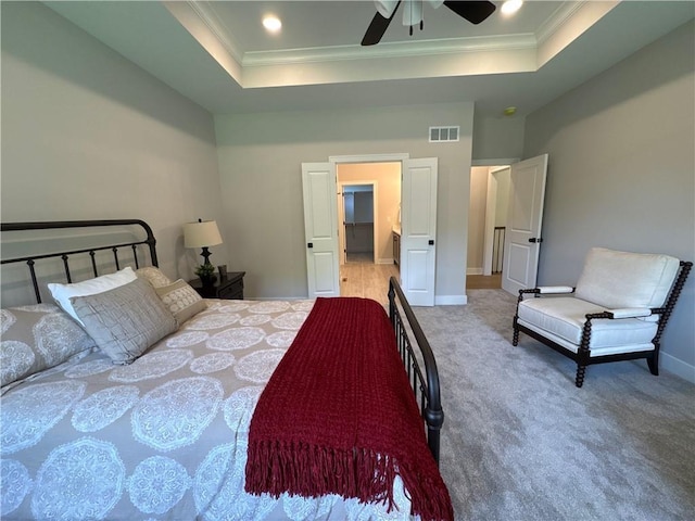 carpeted bedroom with ceiling fan, crown molding, and a tray ceiling