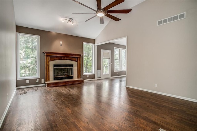 unfurnished living room featuring a tile fireplace, a wealth of natural light, dark hardwood / wood-style floors, and lofted ceiling