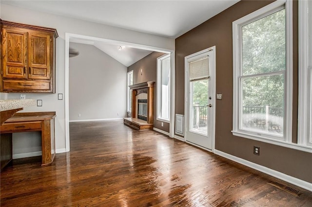 unfurnished living room with dark hardwood / wood-style flooring, a wealth of natural light, and lofted ceiling