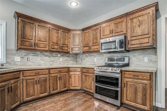 kitchen with tasteful backsplash, dark wood-type flooring, and appliances with stainless steel finishes