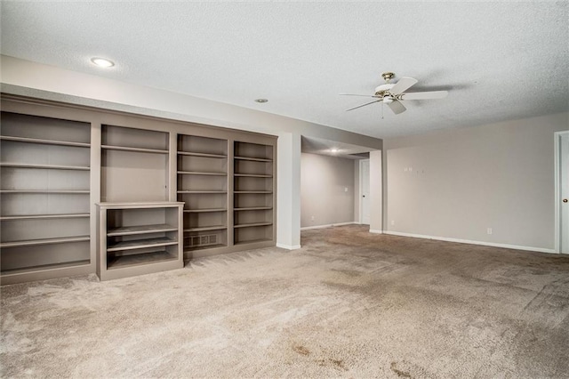 unfurnished living room featuring built in shelves, carpet floors, and a textured ceiling