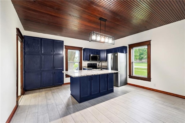 kitchen featuring stainless steel appliances, light stone counters, blue cabinets, decorative light fixtures, and a center island with sink