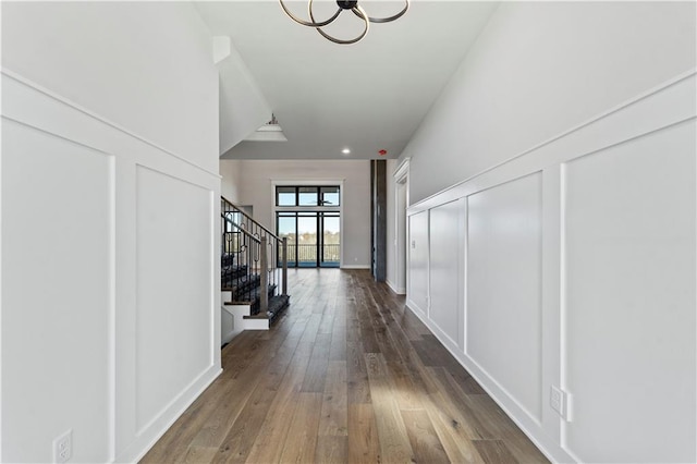 corridor featuring dark wood-type flooring and an inviting chandelier