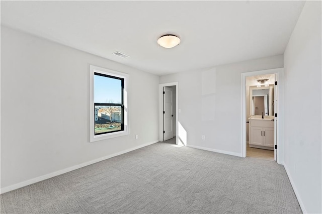 unfurnished bedroom with ensuite bathroom and light colored carpet