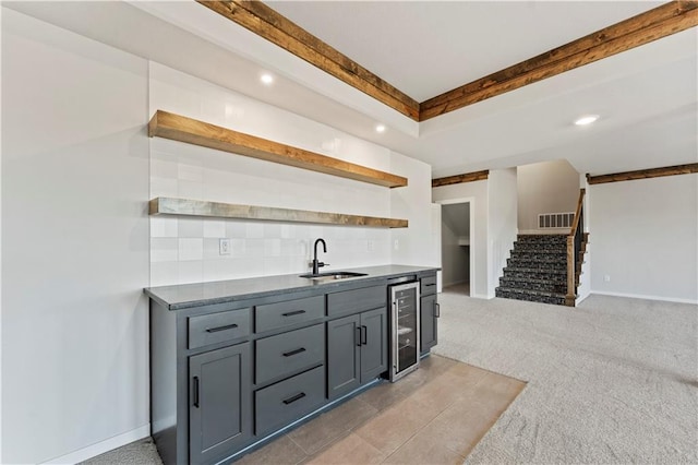 kitchen with light carpet, beverage cooler, gray cabinetry, and sink