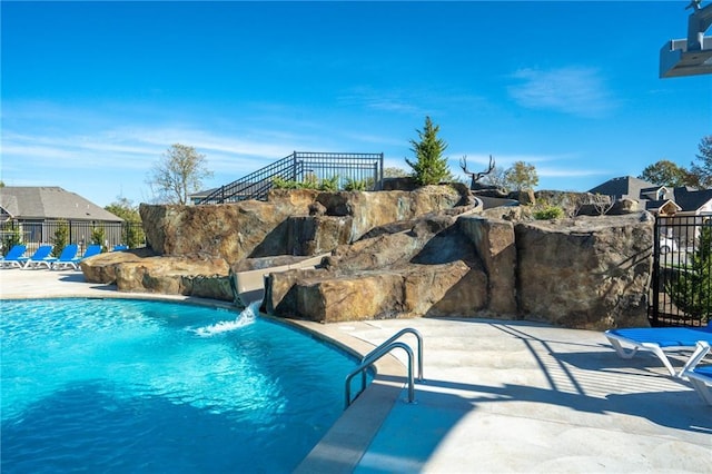 view of swimming pool with pool water feature and a patio area