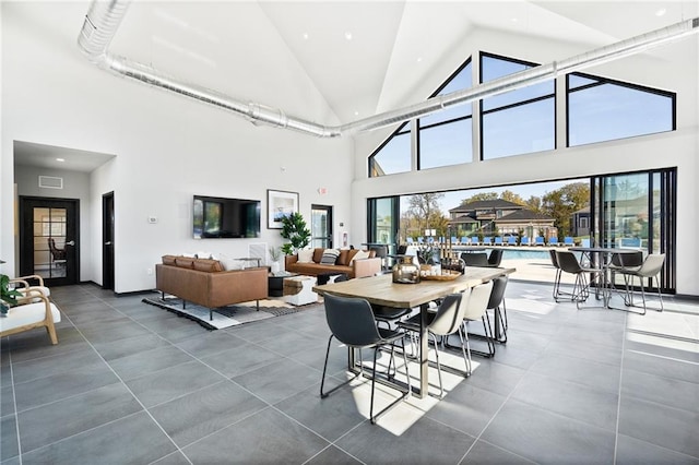 dining area with high vaulted ceiling and dark tile patterned flooring