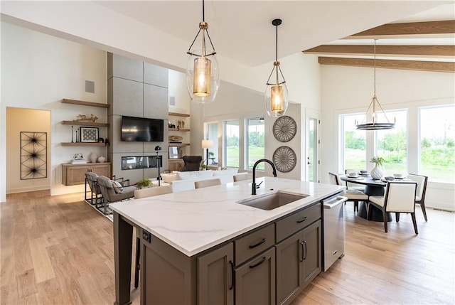 kitchen with beam ceiling, light stone countertops, dishwasher, sink, and hanging light fixtures