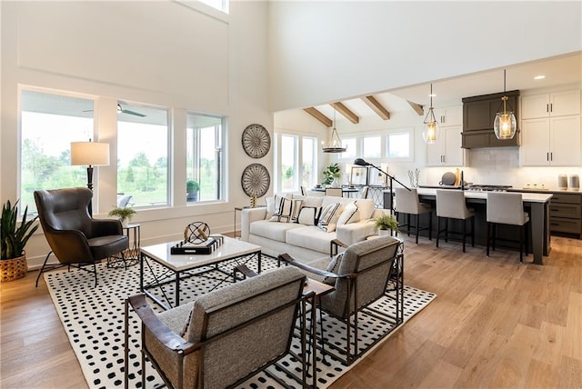 living room with ceiling fan, lofted ceiling with beams, and light wood-type flooring