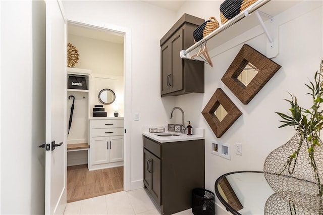 washroom with hookup for a washing machine, sink, light tile patterned floors, and cabinets