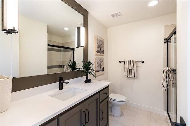 bathroom with tile patterned flooring, vanity, toilet, and a shower with shower door