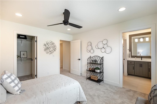 bedroom featuring light carpet, ensuite bathroom, sink, ceiling fan, and a closet