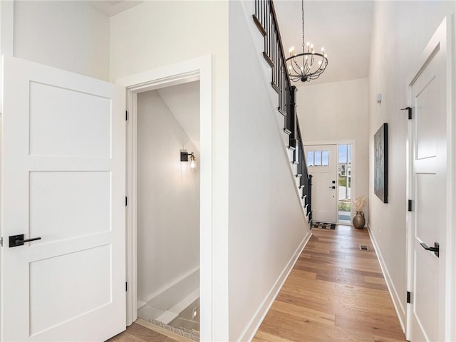 hallway featuring an inviting chandelier and light hardwood / wood-style floors