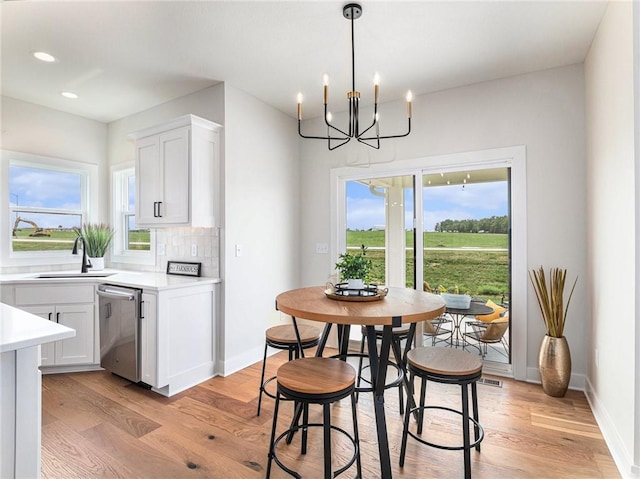 dining area with sink, an inviting chandelier, and light hardwood / wood-style floors