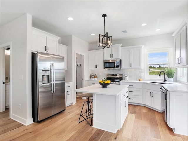 kitchen with appliances with stainless steel finishes, white cabinets, a kitchen island, and sink