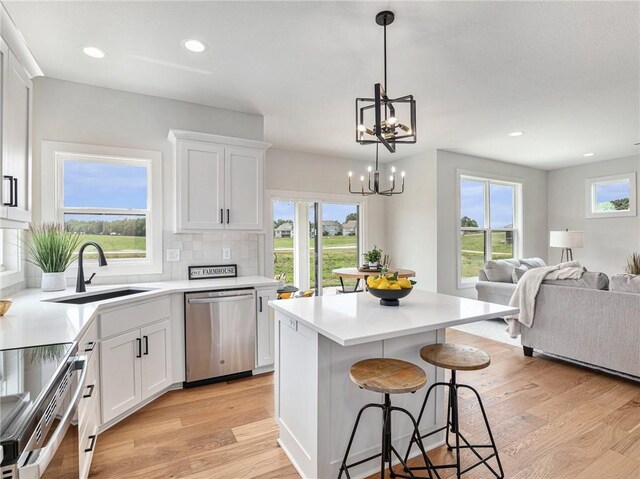 kitchen featuring a center island, white cabinetry, stainless steel appliances, light hardwood / wood-style floors, and backsplash