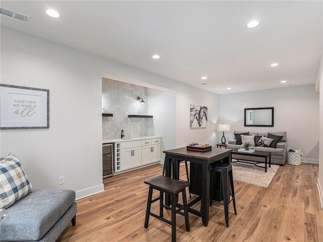 dining room featuring wine cooler, indoor wet bar, and light hardwood / wood-style floors