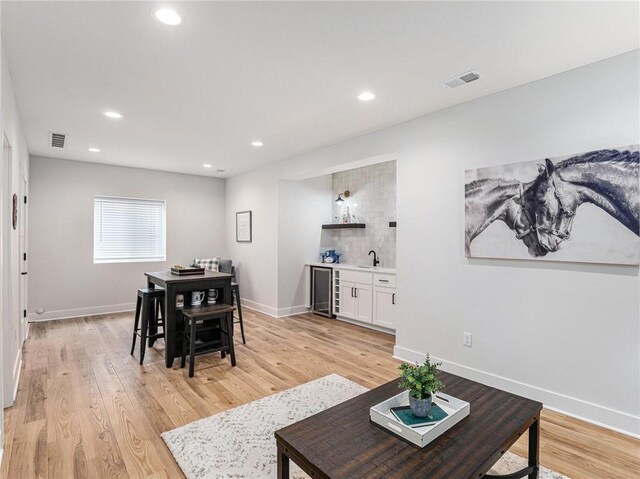 dining space with indoor wet bar, wine cooler, and light hardwood / wood-style floors